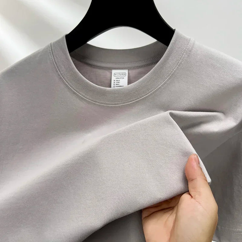 Gray t-shirt held by a hand on a plain background
