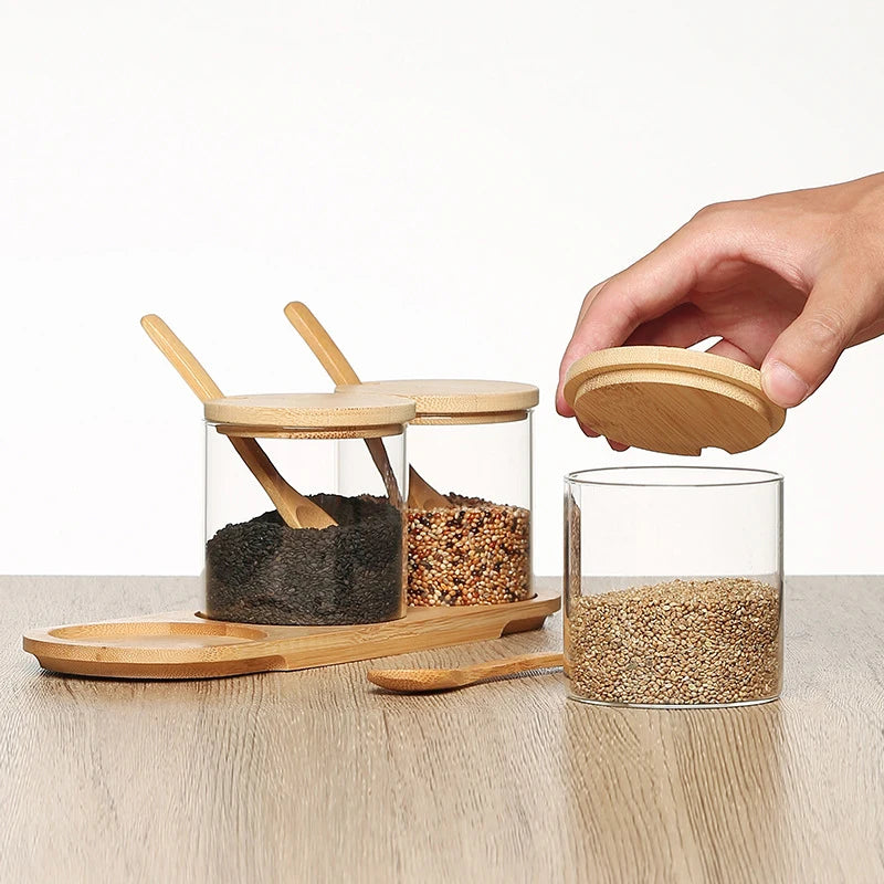 Glass jars with wooden lids and spoons on a wooden surface