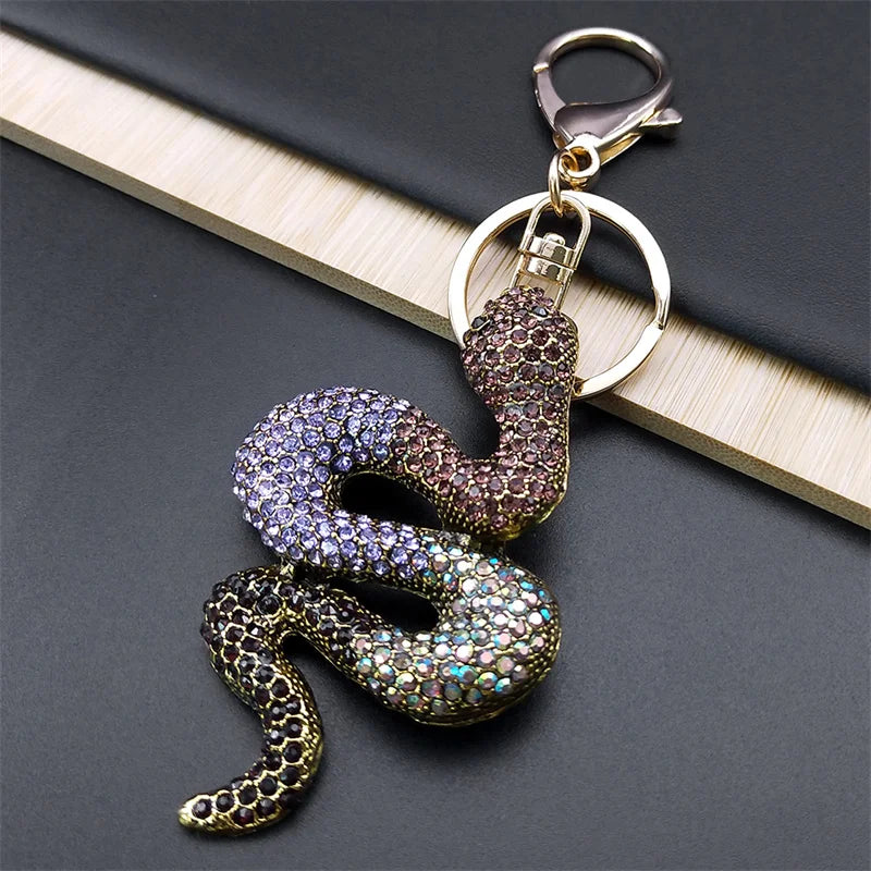 Snake-shaped keychain with rhinestones on a dark surface