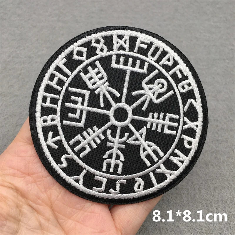 Round patch with Runes held in a hand against a gray background
