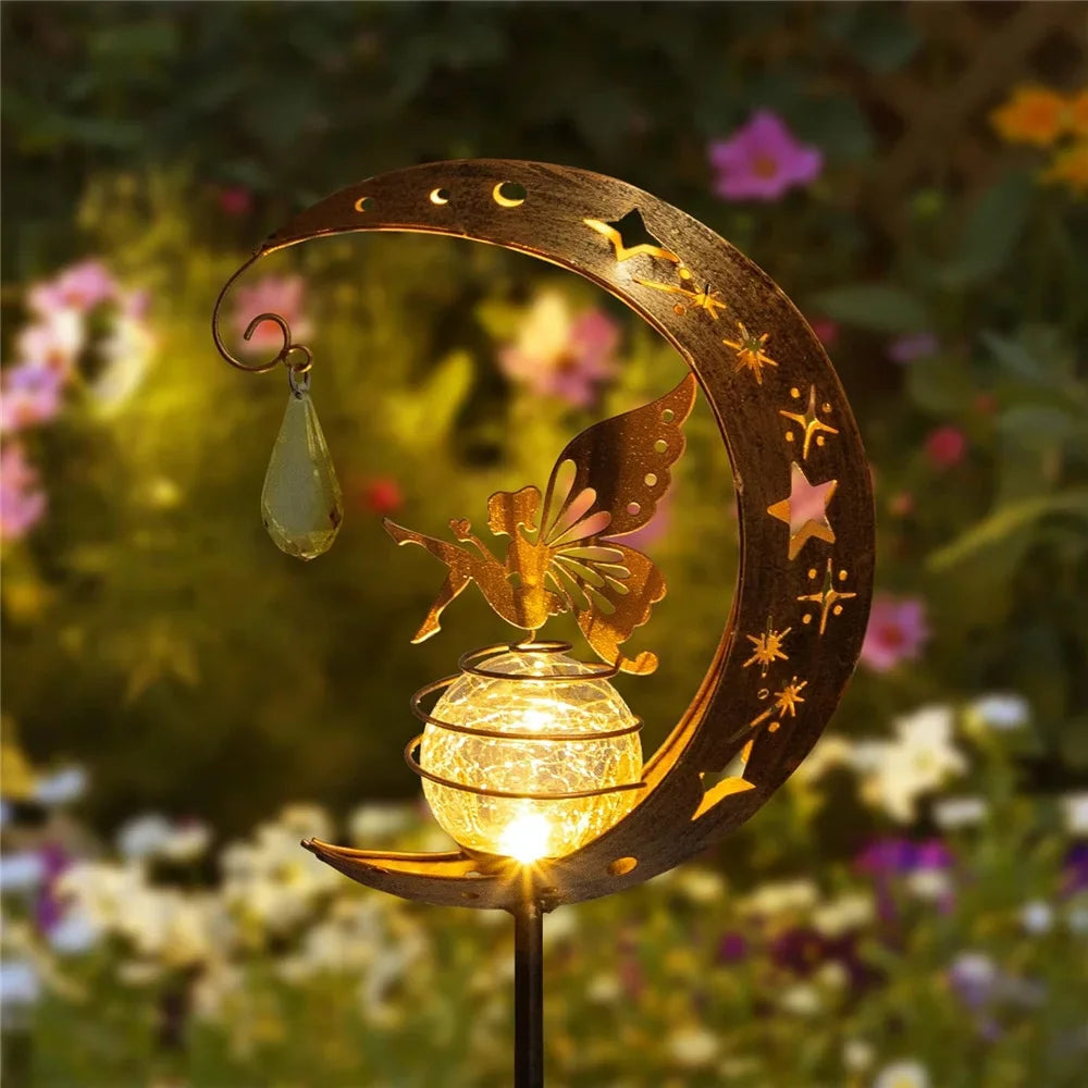 Decorative garden light with moon and butterfly design, glowing in a garden setting.