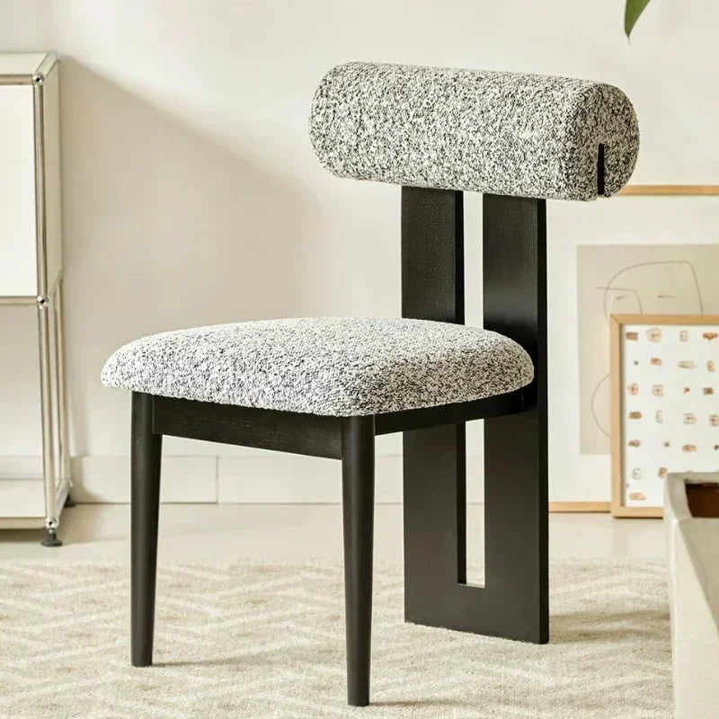 Modern chair with textured gray cushioned seat and backrest in a room setting.