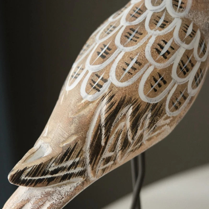 Close-up of a wooden bird sculpture with detailed carvings on a dark background