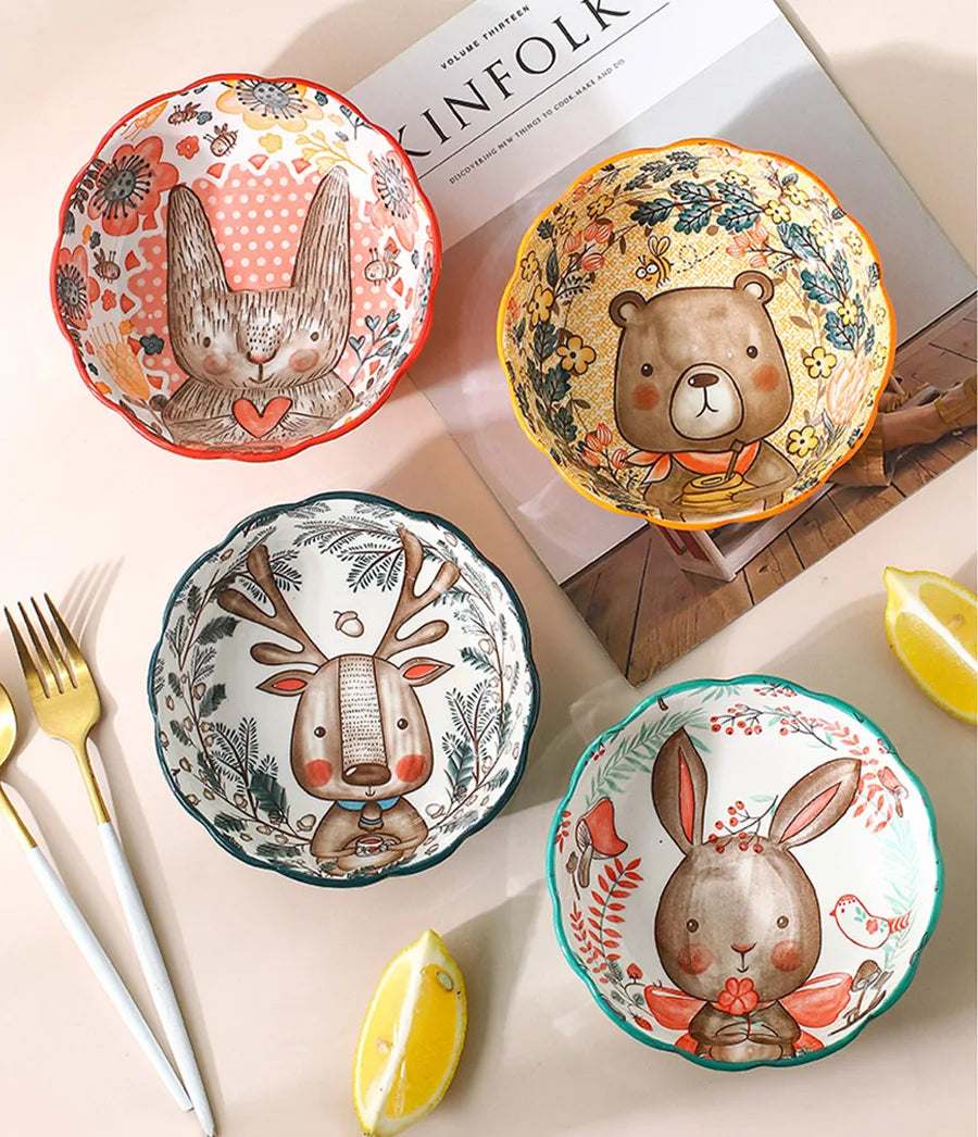 Four ceramic bowls with animal designs on a table with a magazine and lemon slices.