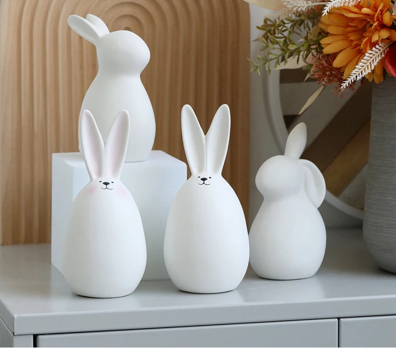 Set of white ceramic rabbit sculptures on a surface with a decorative background