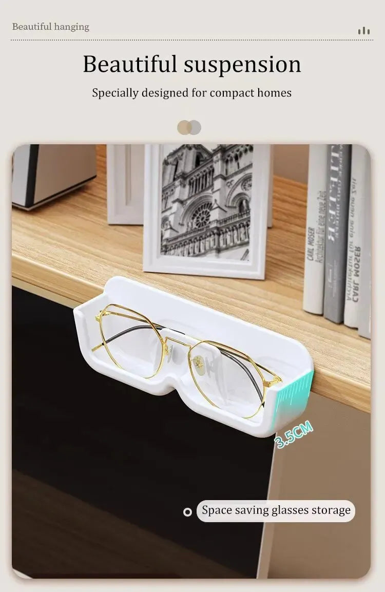 White glasses case with gold-framed glasses on a shelf with books and a photo frame.
