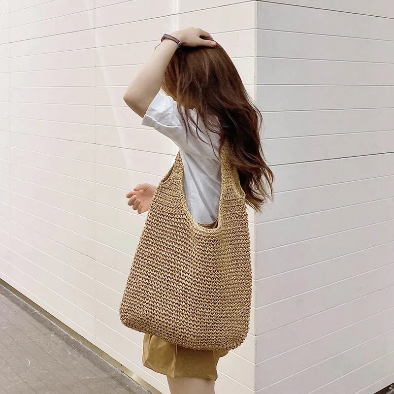 Person holding a woven bag against a white wall