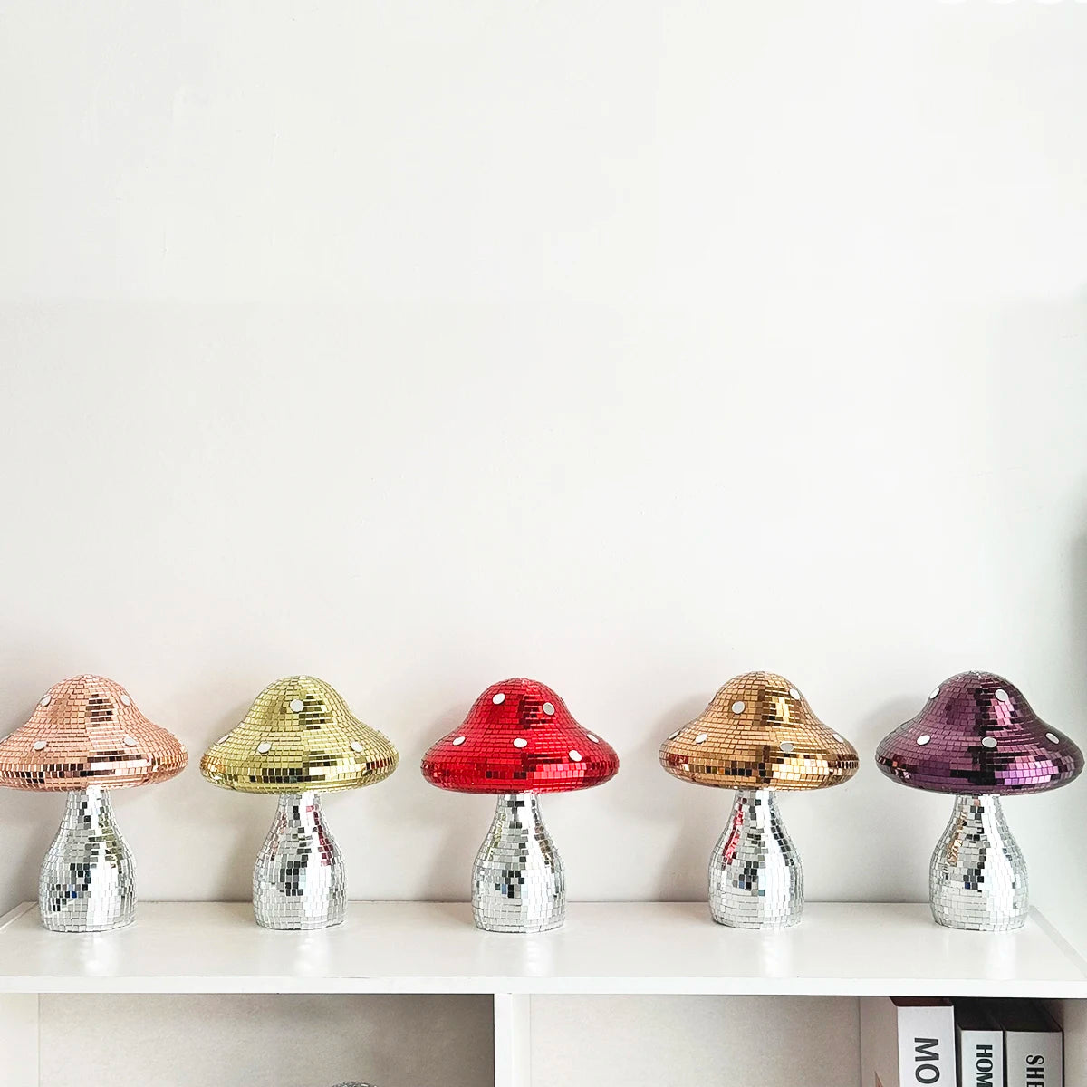 Colourful disco mushroom ornaments with mirrored mosaic tiles and silver reflective stems displayed on a shelf