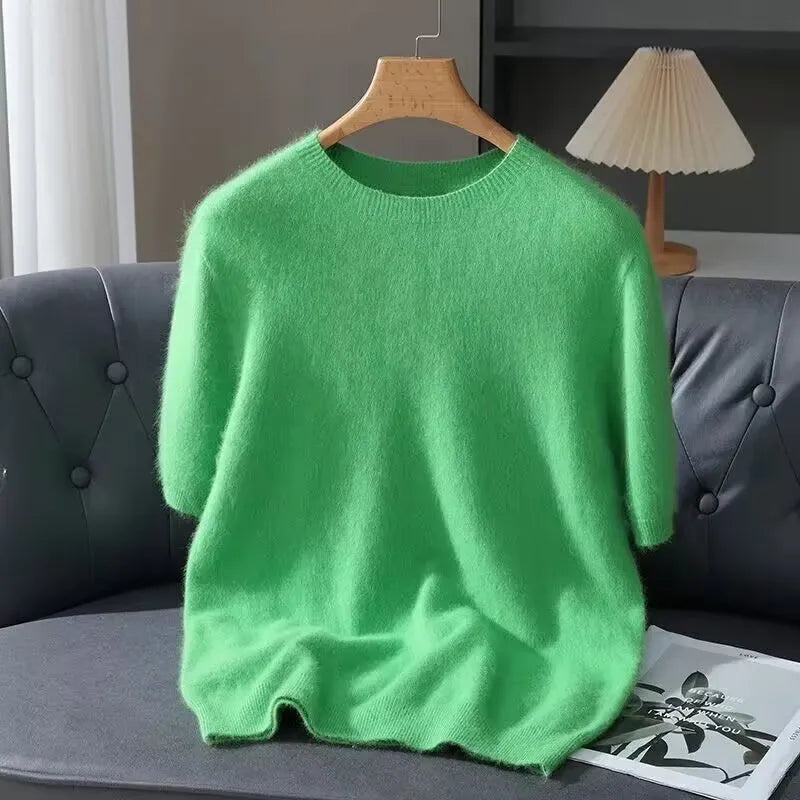 Green sweater on a hanger against a gray sofa and lamp background
