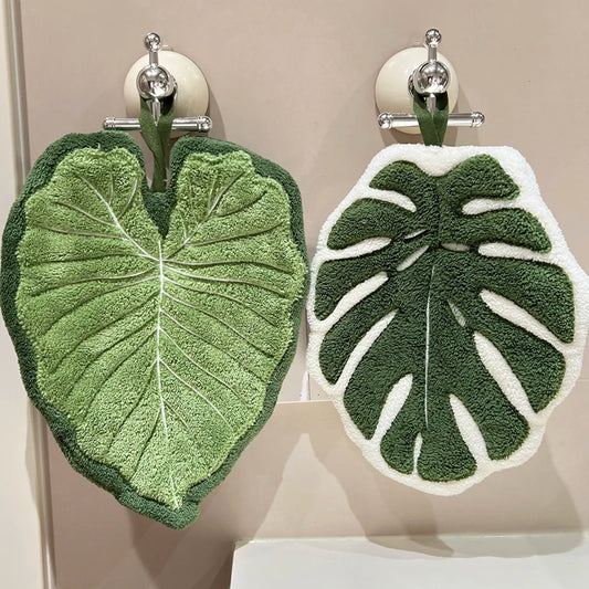 Leaf shaped hanging hand towel made from soft coral fleece fabric displayed beside a bathroom sink