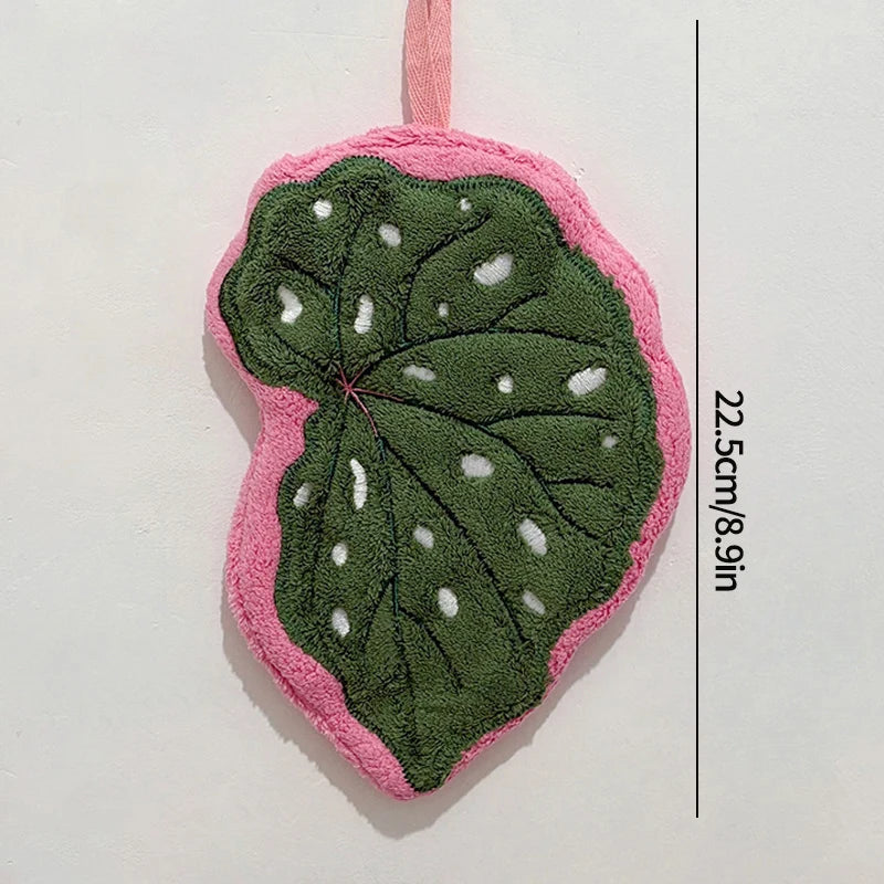 Leaf shaped hanging hand towel made from soft coral fleece fabric displayed beside a bathroom sink