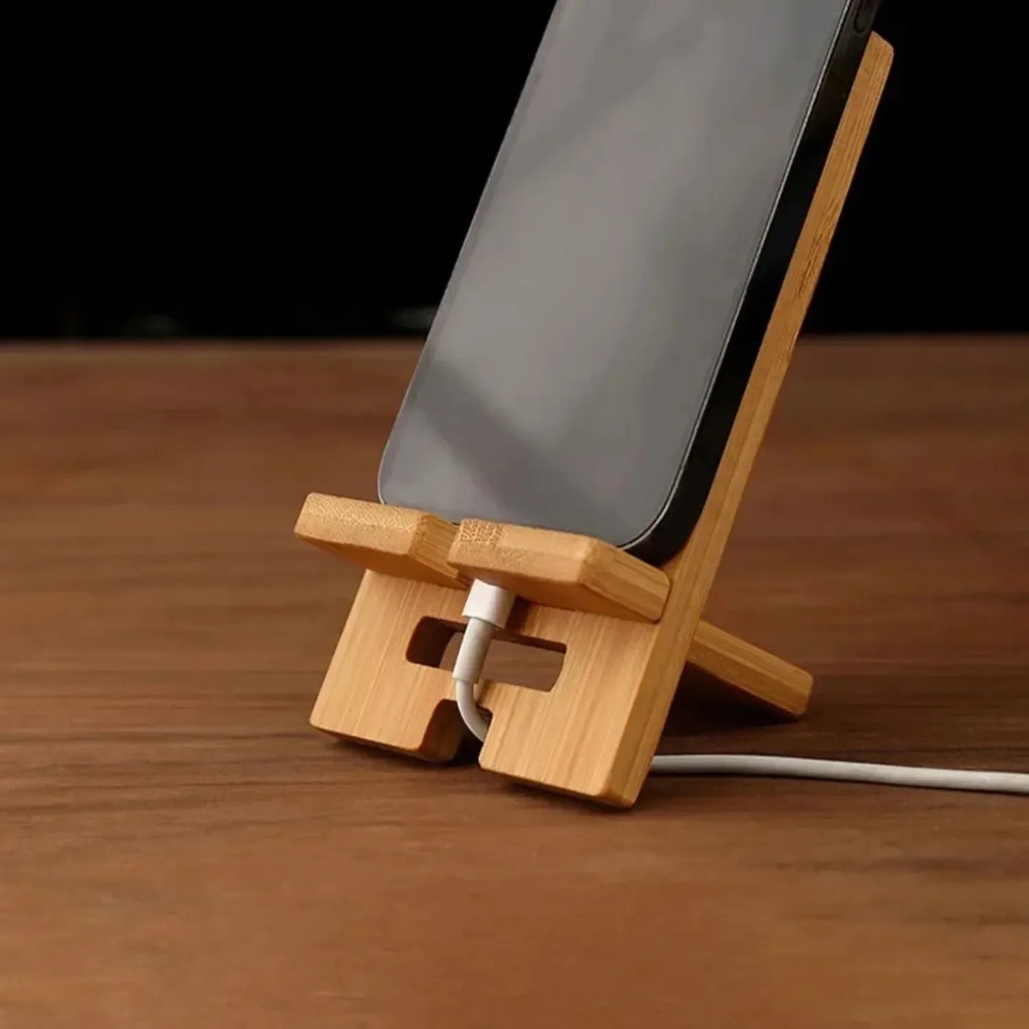 Wooden phone stand holding a smartphone on a wooden surface