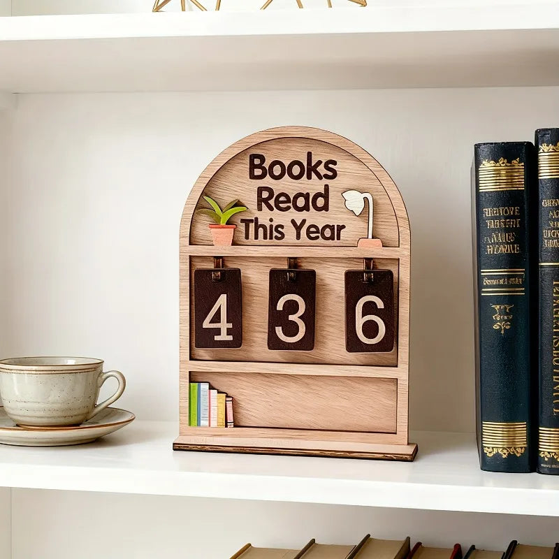 Wooden plaque with 'Books Read This Year' display on a shelf with books and a cup.