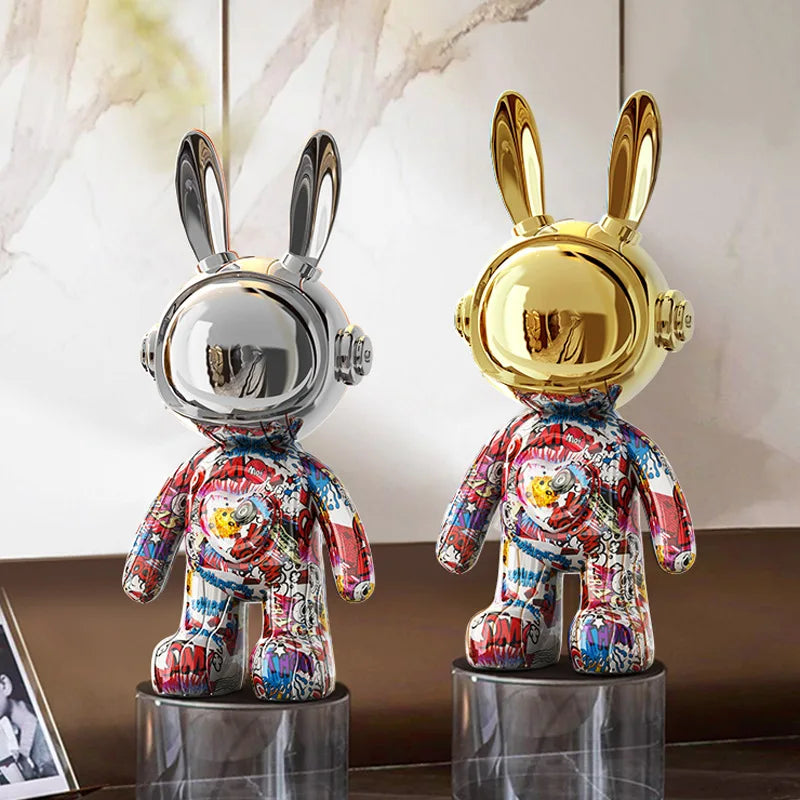Two decorative figurines of rabbits in space suits on a reflective surface with a neutral background.