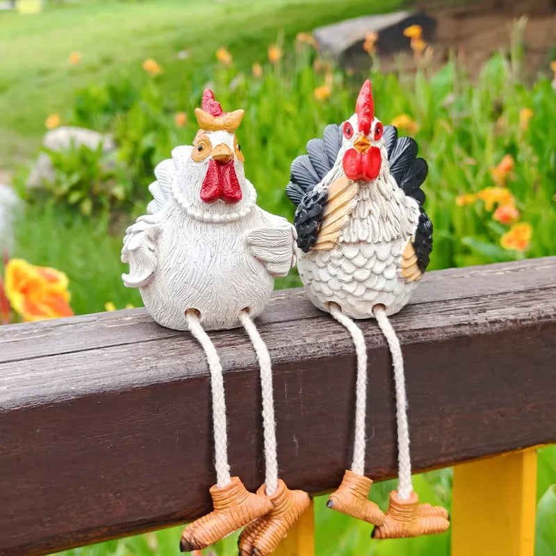 Two decorative rooster figurines on a wooden surface with a garden background.