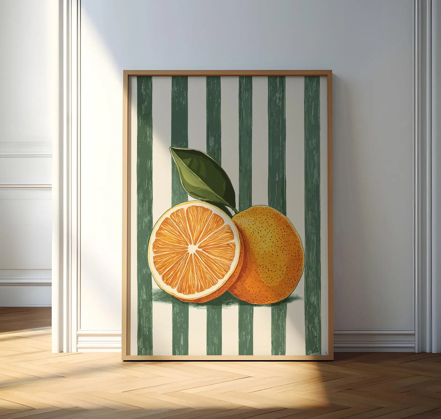 Framed artwork of two oranges on a striped background in a room with wooden flooring.