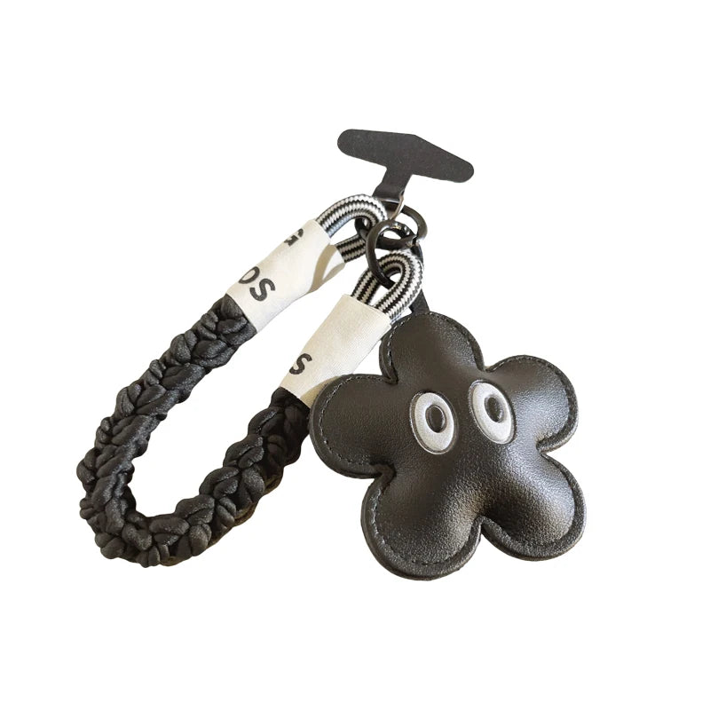 Black flower-shaped keychain with braided design on a white background