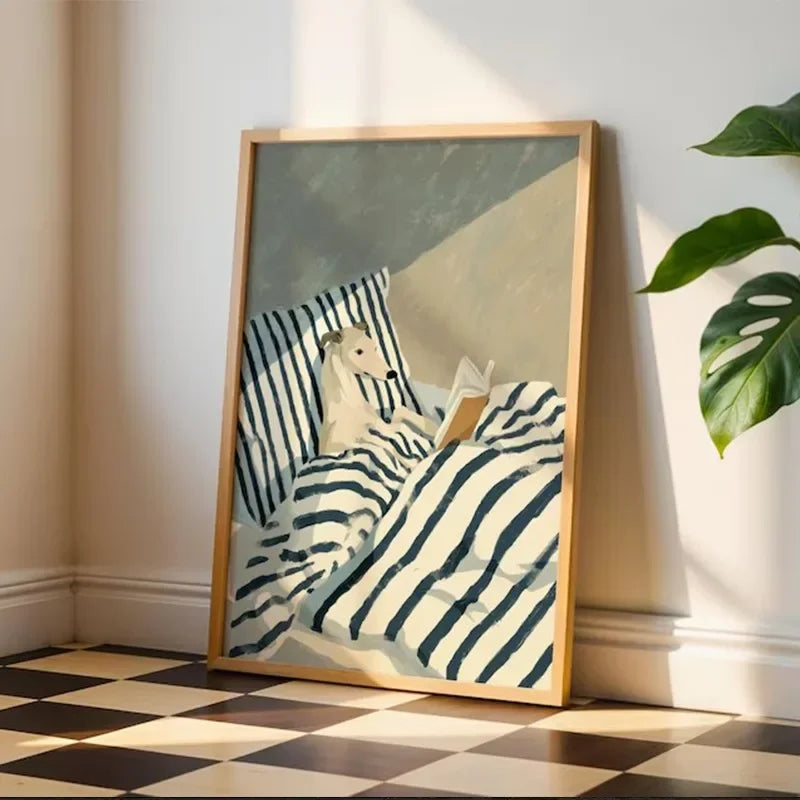 Framed artwork of a person reading a book on striped bedding, leaning against a wall with a plant to the side.