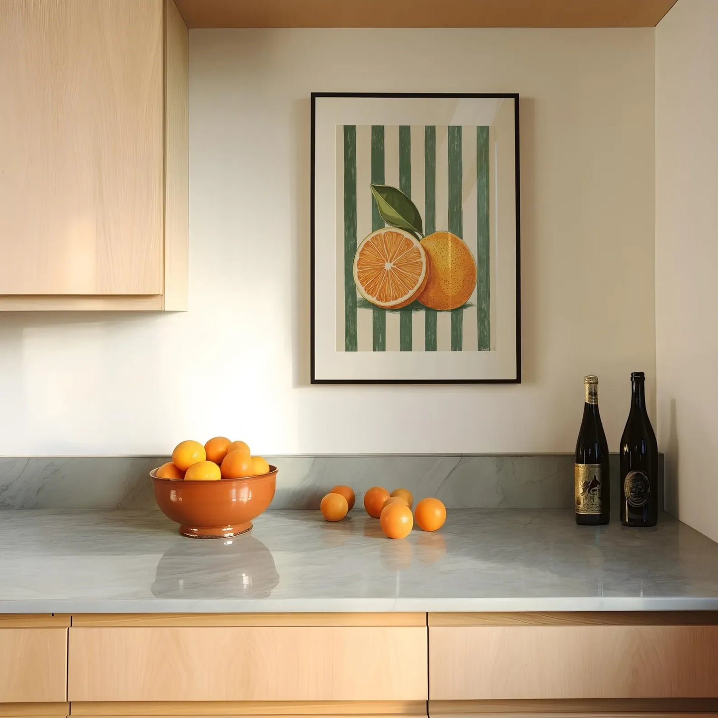 Kitchen counter with a bowl of oranges, a bottle of wine, and a framed picture of oranges on the wall.