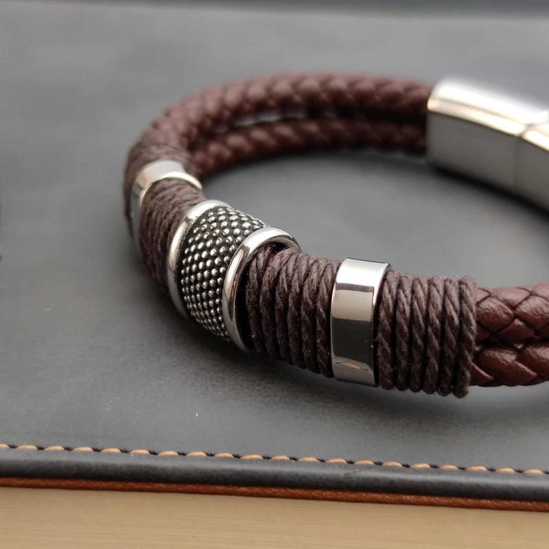 Brown braided leather bracelet with silver metal accents on a dark surface