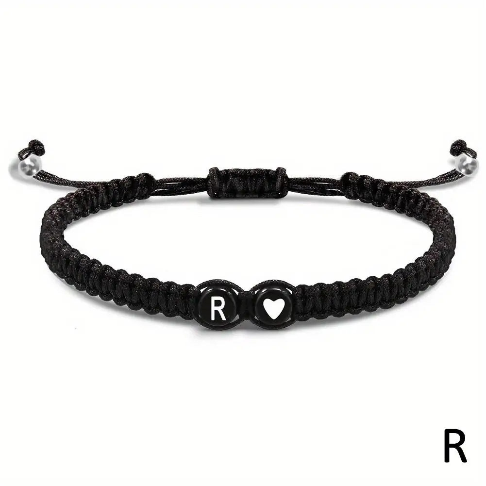 Black braided bracelet with letter 'R' charm on a white background