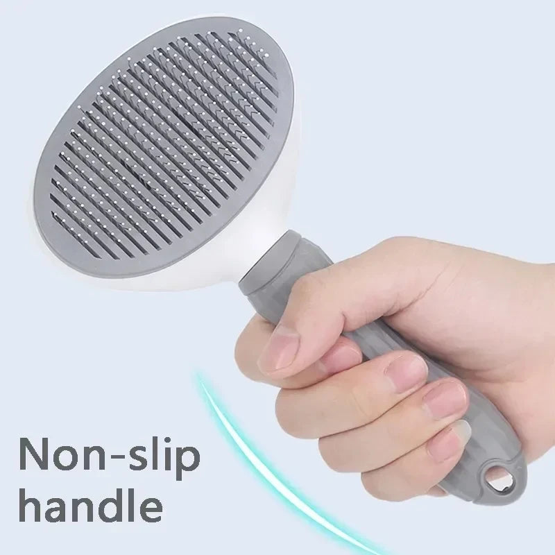 Hand holding a gray pet grooming brush with a non-slip handle on a light blue background.