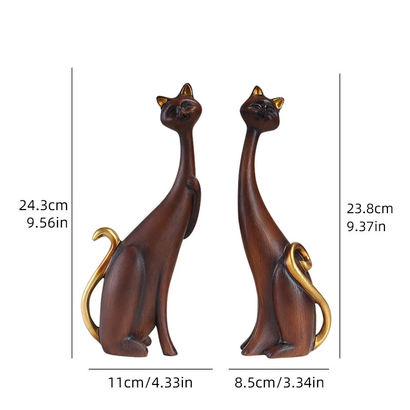 Pair of decorative resin cat sculptures with elongated modern silhouettes and artistic finishes, displayed as contemporary home decor on a tabletop.