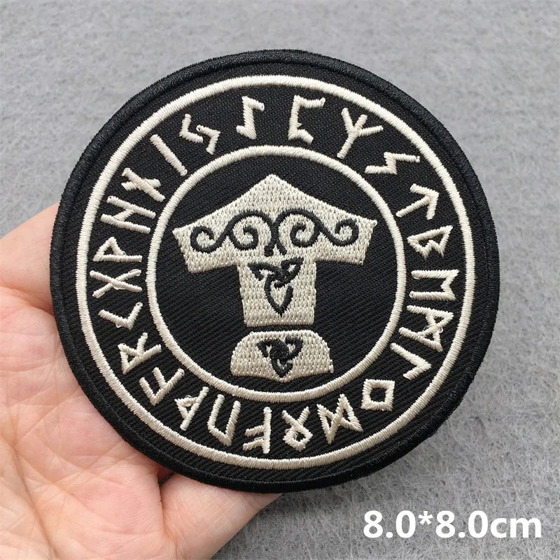 Round patch with symbols and text held by a hand on a gray background