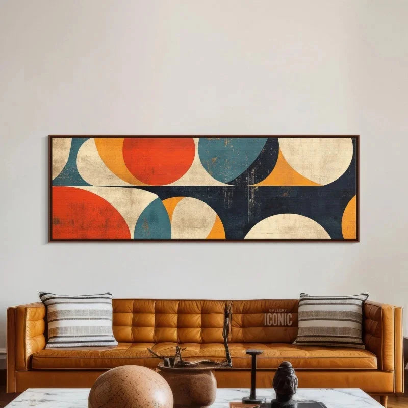 Abstract wall art above a sofa in a living room setting abive a long brown leather sofa