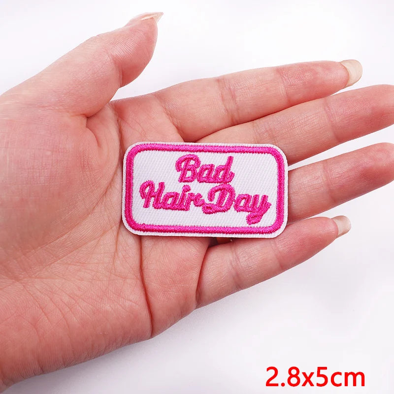 Patch with 'Bad Hair Day' text held in a hand on a white background