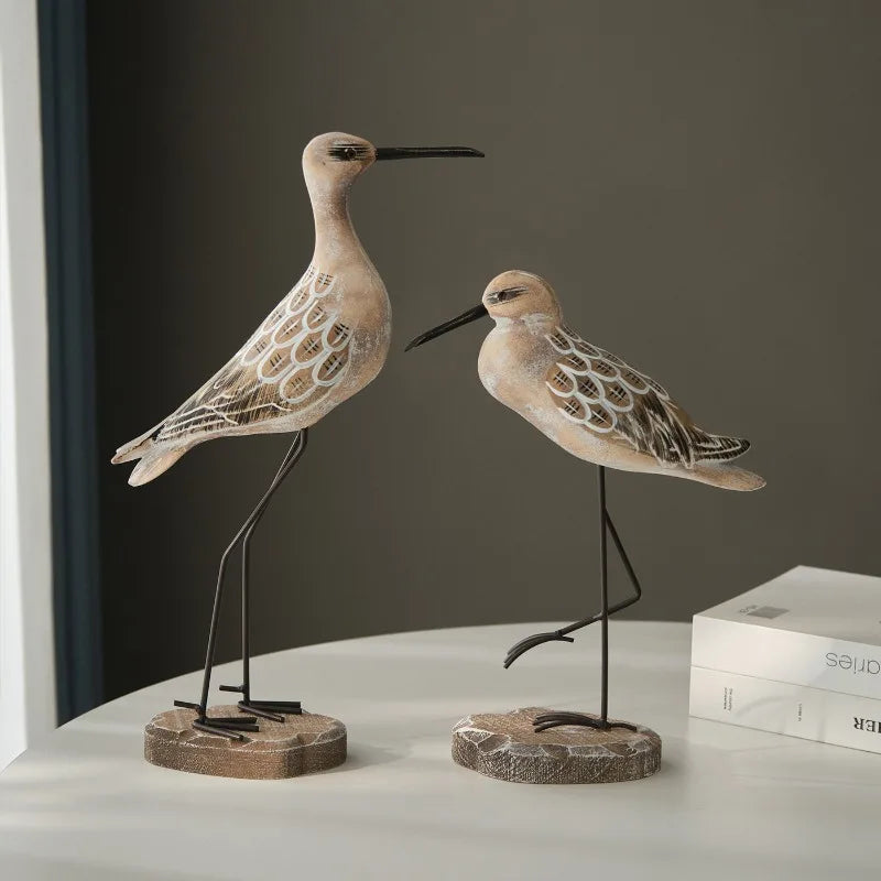 Two decorative bird figures on stands against a plain background