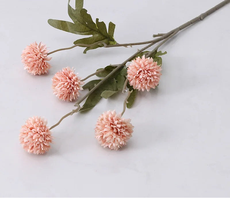 Pink artificial flowers with green leaves on a light gray background