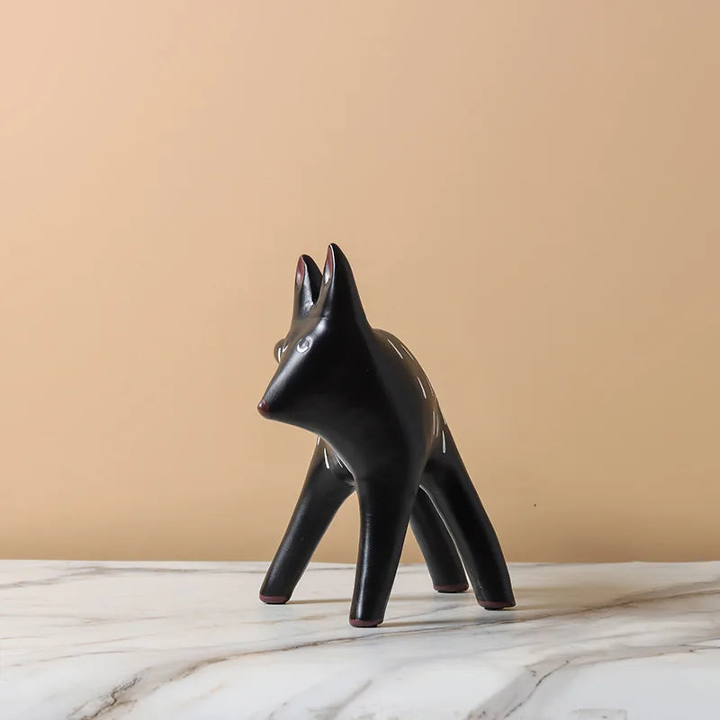 Black ceramic fox figurine on a marble surface with a beige background
