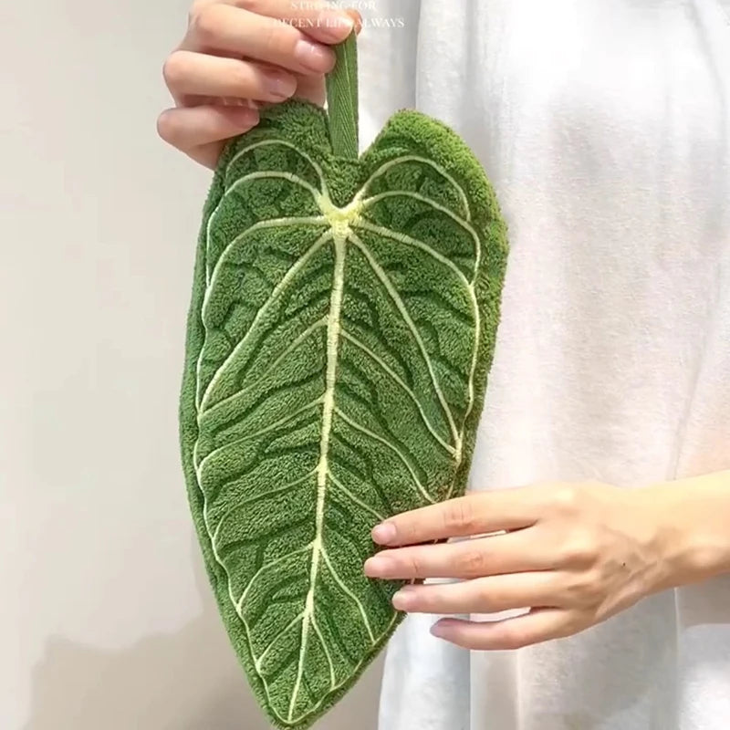 Green leaf-shaped towel held by a person against a white background