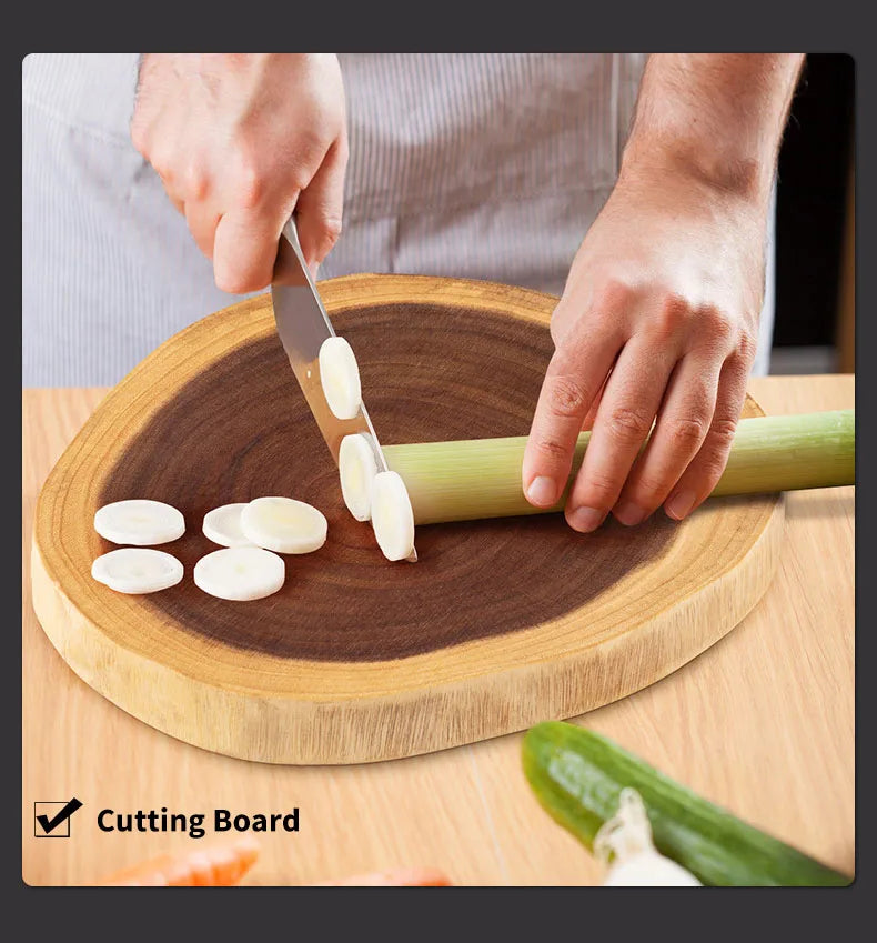 Person slicing green onions on a wooden cutting board with a knife.