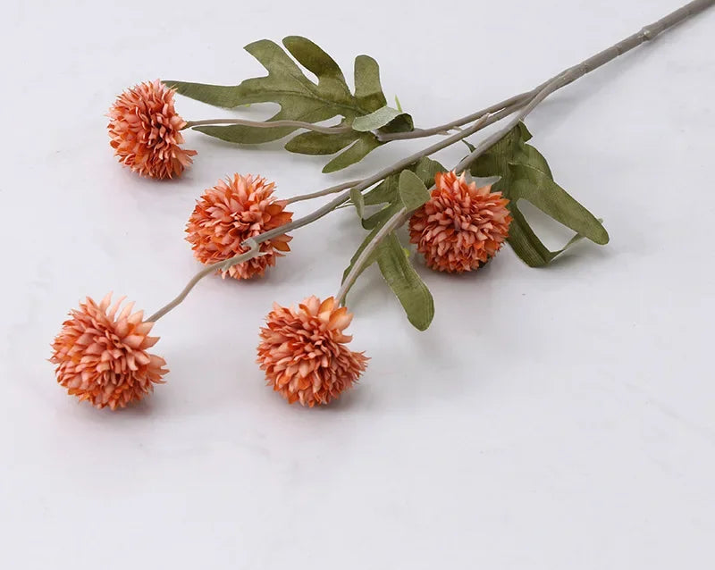 Artificial flower branch with orange flowers and green leaves on a white background