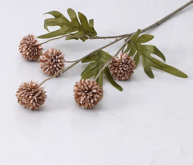 Decorative branch with brown spherical flowers and green leaves on a light gray background