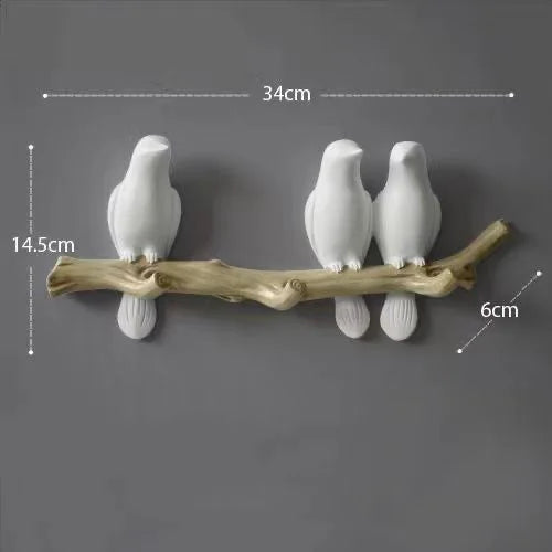 Decorative wall hook with three white birds on a branch against a gray background