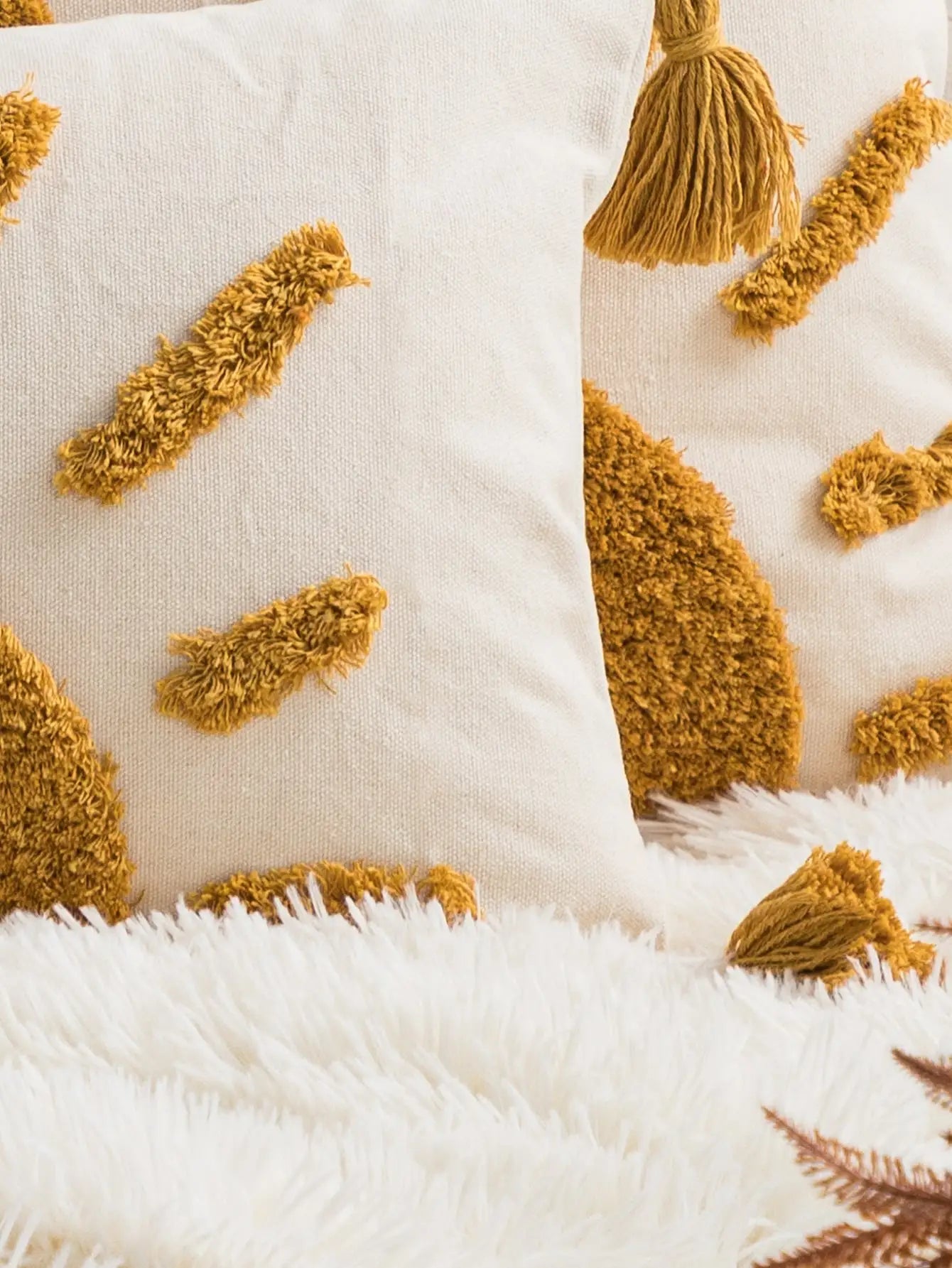 Close-up of textured pillows with tassels on a white background