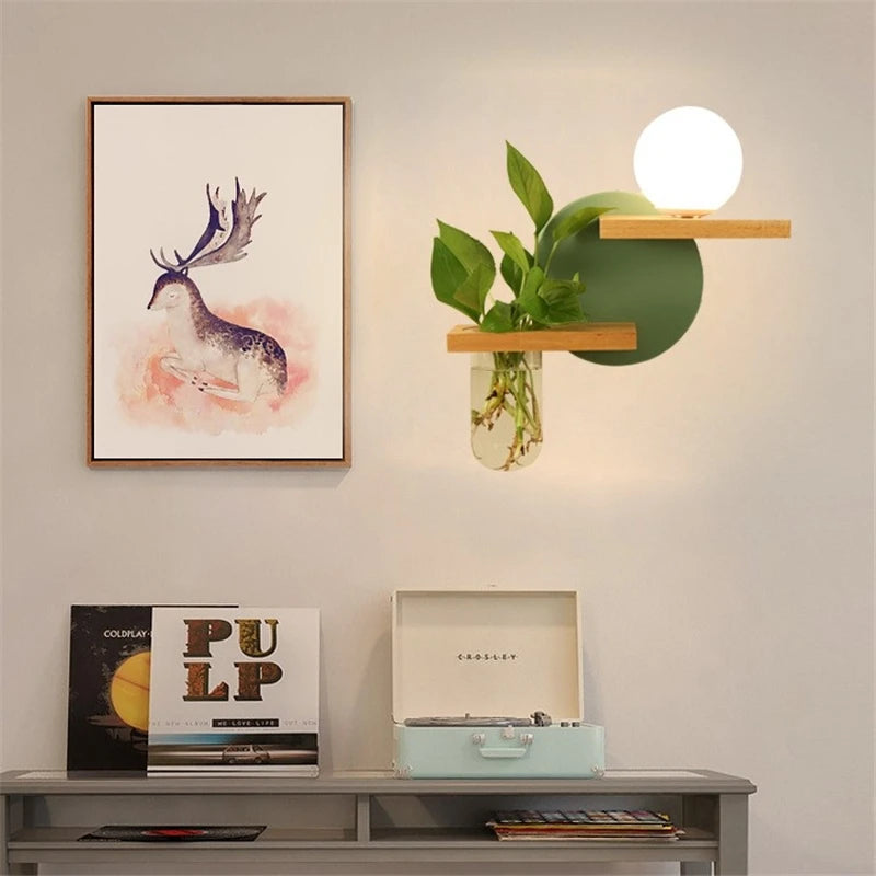 Decorative setup with a framed picture of a deer, a record player, and a wall-mounted plant on a light gray wall.