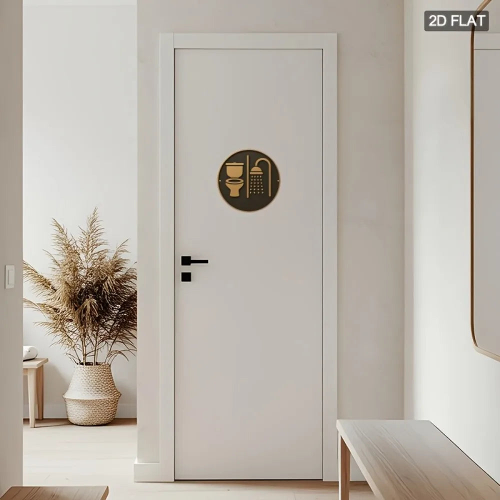 White door with a gold circular decal featuring bathroom icons, flanked by a plant and bench in a minimalistic room.