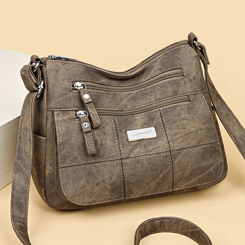 Brown handbag with multiple zippers on a beige background