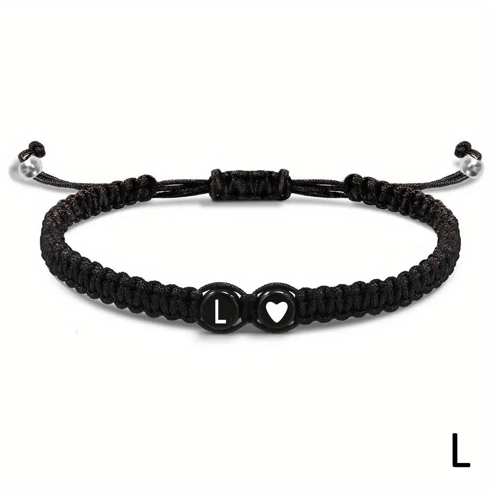 Black braided bracelet with heart and lock charm on a white background