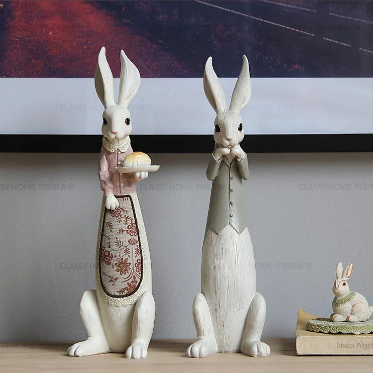 Decorative rabbit statues on a shelf with a neutral background