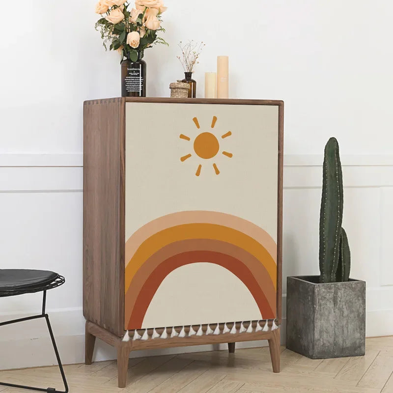 Wooden cabinet with sun and rainbow design next to a cactus plant indoors.