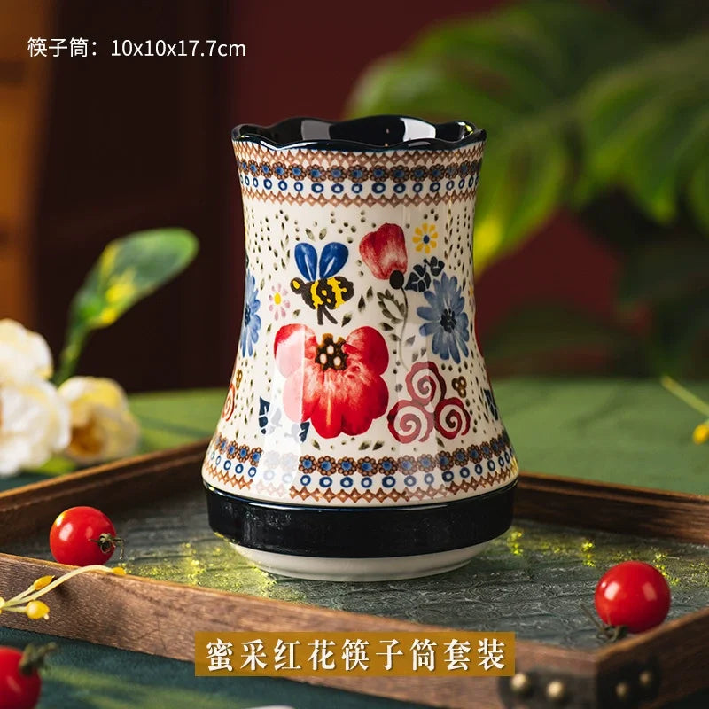 Decorative ceramic vase with floral patterns on a wooden tray with red berries.