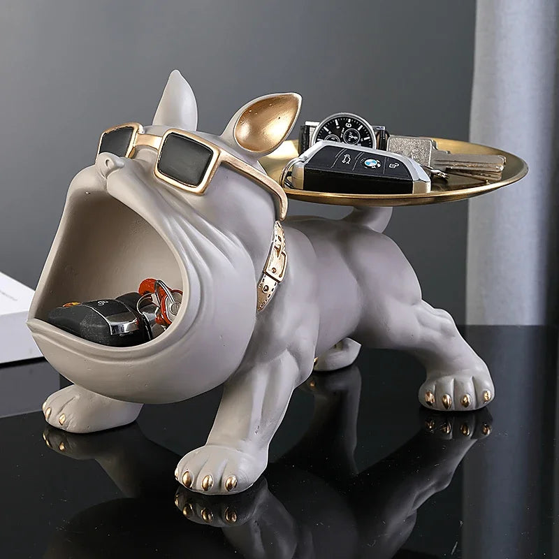 Decorative bulldog figurine with sunglasses and a tray on a reflective surface.