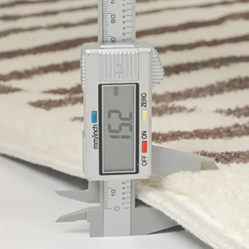 Digital caliper measuring a fabric sample with a striped background