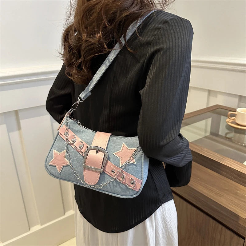 Person wearing a denim handbag with pink star designs and buckles.