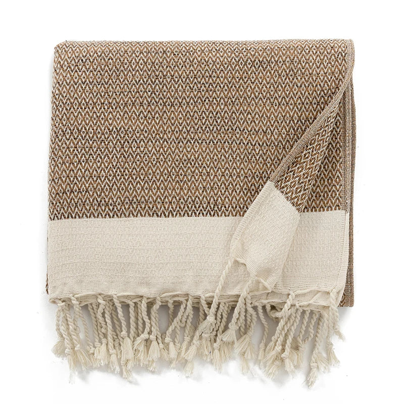 Beige and white patterned throw with fringes on a white background